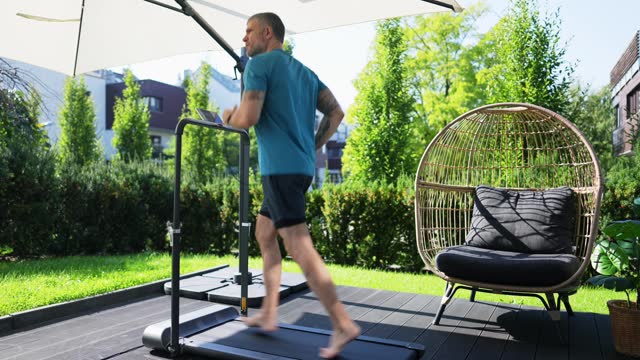 Man running on a treadmill at the porch of his house