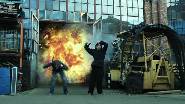 Slow-motion scene from an action movie of two boys in a moment of a big explosion behind them