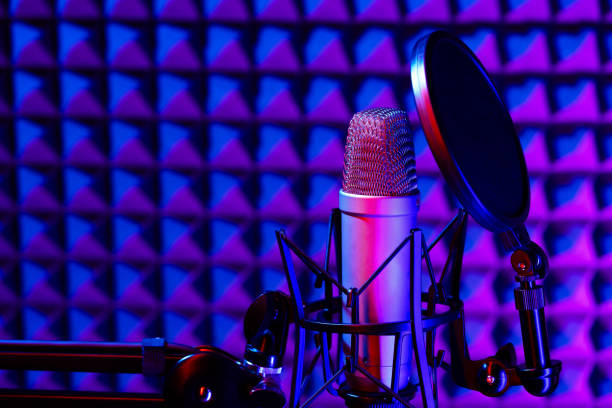 istock Professional studio microphone against acoustic foam panel background in neon light 1951858504