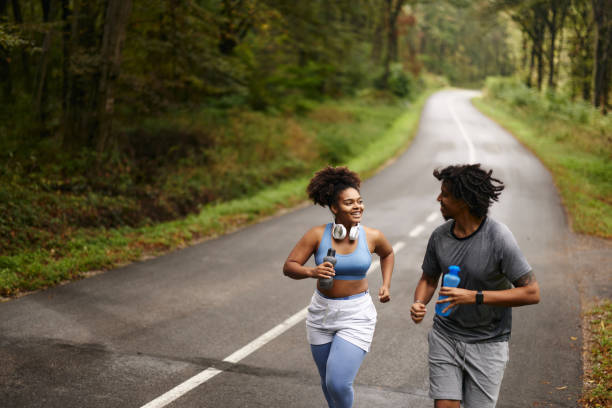 istock Happy black couple of athletes talking while running on empty road. 1951861274