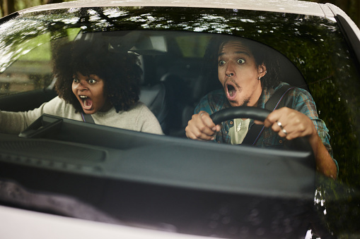 African American couple feeling shocked while about to crash in a car. The view is through windshield.