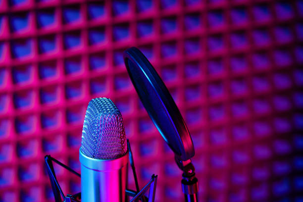istock Professional studio microphone against acoustic foam panel background in neon light 1951867729