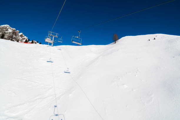 A group of adventurous skiers brave the freezing temperatures as they ascend a snowy mountain on a ski lift, surrounded by glacial landforms and a stunning winter sky