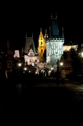 A group of turist walk in the dark, gazing up at the majestic castle tower as Prague city lights danced in the night sky above