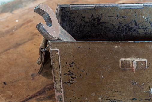 An abandoned wrench rests in a rusted metal box, its once sharp plane now grounded by the passage of time