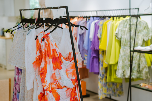 Women's clothing summer collection on hangers hanging in a boutique.