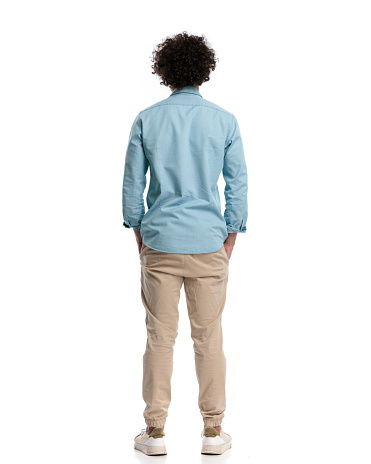 back view of relaxed young man with curly long hair standing on isolated background