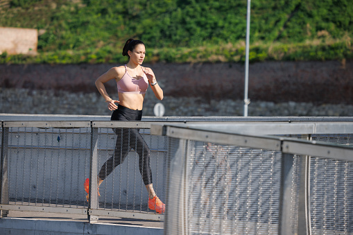 Young woman taking up outdoor fitness activities, jogging on a fine day at springtime