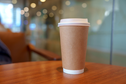 Brown paper cup of hot coffee in cafe. Take away, Enjoy beverage, Relax time with hot drinks.