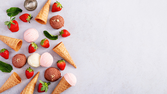 Frame with ice cream, cones with chocolate, vanilla and strawberry taste, flat lay on light gray table, top view