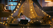 Home, night and girl with a tablet, tent and relax with fairy light, connection and social media. Kid, playful and child with technology, cartoon or internet with peace, digital app or online reading