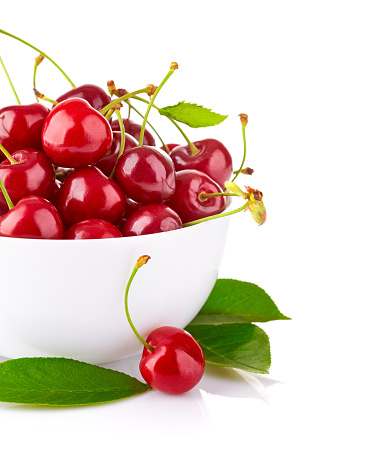 Fresh cherry berries with green leaves isolated on white background. Berry in a bowl.