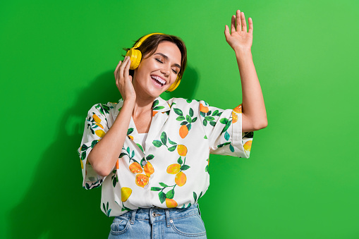 Photo attractive energetic young girl dj listening new release spotify mix music test orange headphones isolated on green color background.
