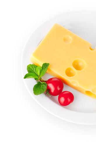 Yellow cheese with red tomatoes and green mint leaves on the white plate. Organic natural food ingredients isolated background.