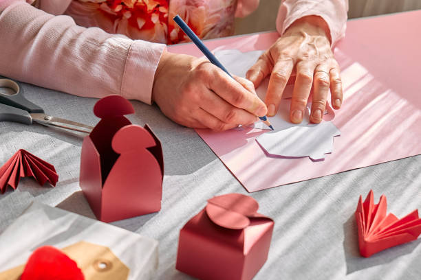 istock Paper craft diy. Woman's hands making handmade heart shaped gift box for Valentines day, birthday, Mothers day, wedding. 1951982425