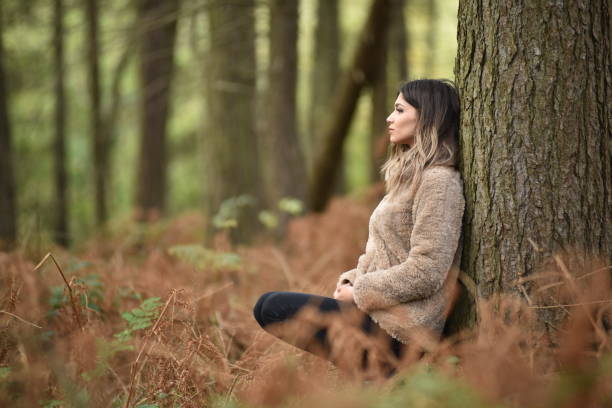 istock Young woman leaning on a tree in a lush forest 1951982441