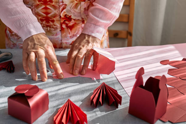 istock Paper craft diy. Woman's hands making handmade heart shaped gift box for Valentines day, birthday, Mothers day, wedding. 1951989504
