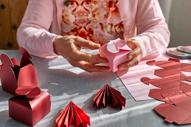 istock Paper craft diy. Woman's hands making handmade heart shaped gift box for Valentines day, birthday, Mothers day, wedding. 1951990596