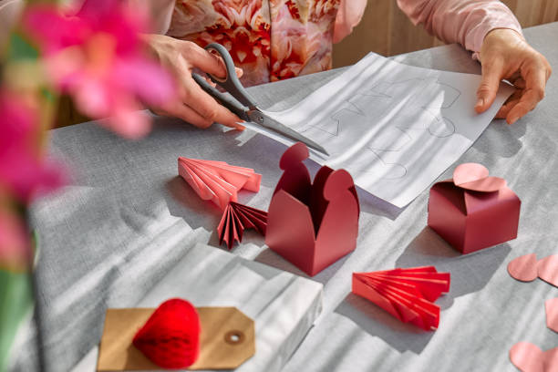 istock Paper craft diy. Woman's hands making handmade heart shaped gift box for Valentines day, birthday, Mothers day, wedding. 1951993263