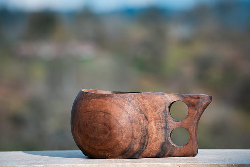 Wooden coffee mug on the handle of the mountain villa balcony.