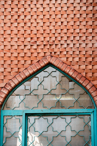 The pattern of the prominent brown stonework wall of the Iranian mosque along with the window.