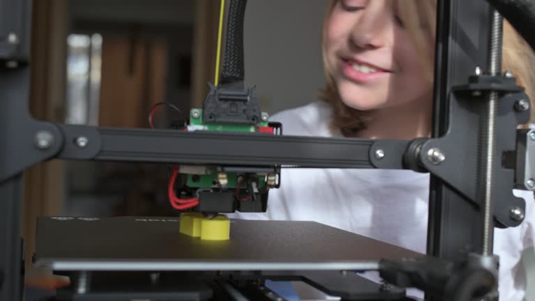 A 10-year-old boy watches the 3D printing process with rapt attention