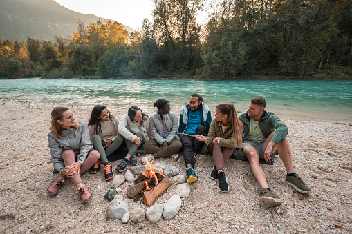 Amidst the beauty of the woods, a diverse group of friends shares the warmth of a bonfire, creating an atmosphere of camaraderie and joy. The forest setting becomes the perfect backdrop for their cherished moments together.