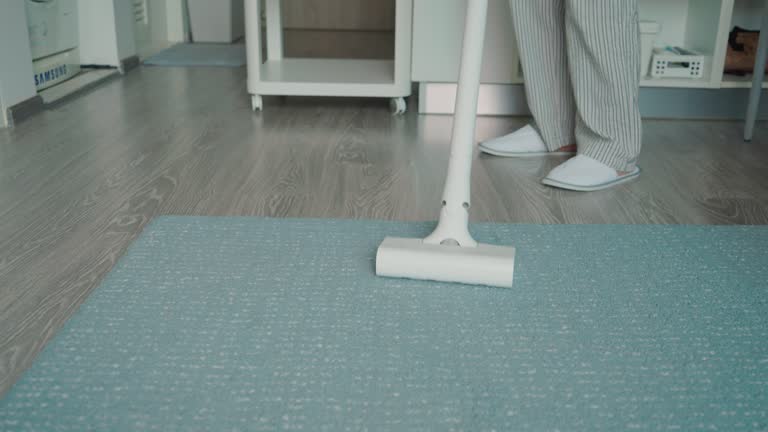 Housewife vacuuming a carpet in living room