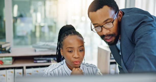istock Computer, black woman and manager training or coaching employee and helping with project, work or collaboration in Nigeria. Mentor, corporate intern and talking about a question, error or pc learning 1952045885