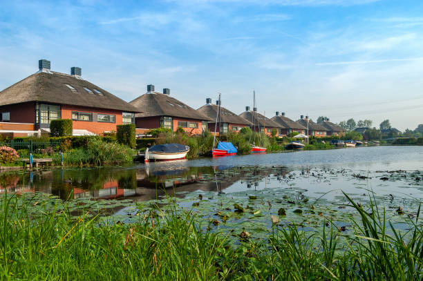Semi detached houses with boats along a canal in the Netherlands on a sunny summer day