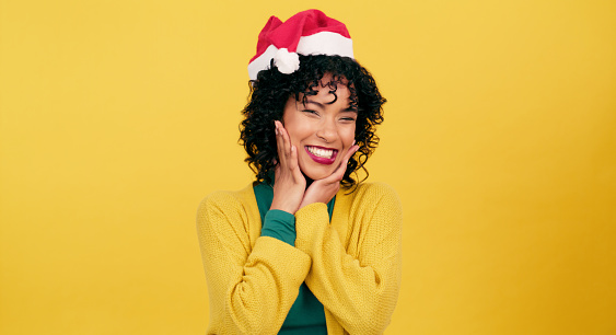 Happy woman, portrait and Christmas hat for surprise, joy or festive season on a yellow studio background. Face of female person smile for holiday cheer, December or special deal on mockup space