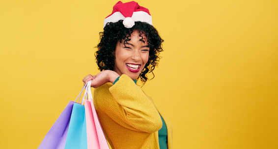 Retail sale, portrait and happy woman with shopping bag in studio for deal, offer or store promotion on yellow background space. Face, smile and female customer with mall, cashback or Christmas gift
