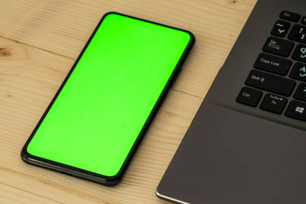 istock Smartphone on wooden desk with green screen. 1952081915