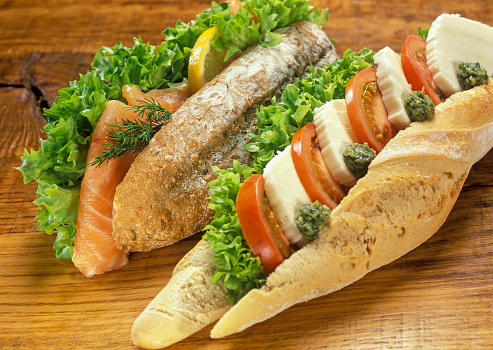 Baguette, one with mozzarella, pesto and tomato. And one with salmon. High angle view.