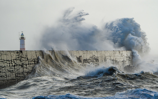 Waves crash against the Breakwater of Newhaven Harbour during a storm. Dramatic scenes as waves and spray are sent into the air by the force of the waves.