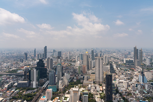Aerial view of Bangkok with houses and office buildings, skyscrapers and city roads under cloudy sky. Drone photo shot of Thailand capital cityscape under cloudy sky