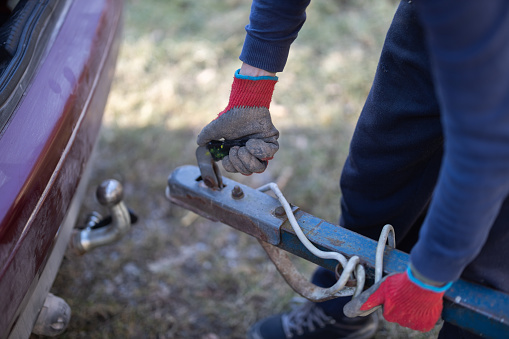 Adult Women's Hands Connect a Trailer to a Car Tow Hitch