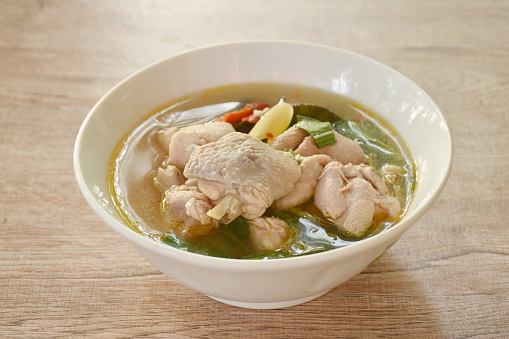 spicy boiled chicken and bone with herb leaf tom yum soup on bowl
