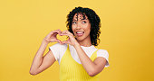 Heart, hands and woman in studio with gesture of love, romance or thank you sign on yellow background. Finger, frame and female model with emoji shape for kindness, gratitude or icon for support