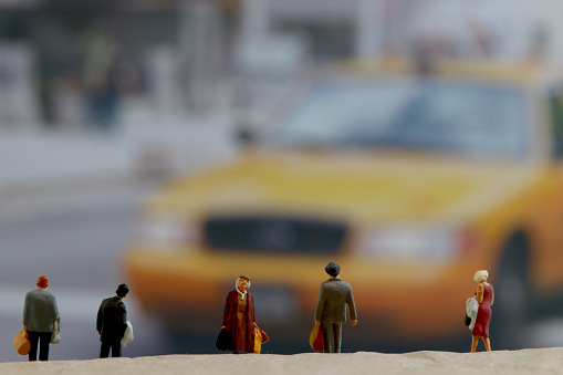 Model people in front of yellow taxi