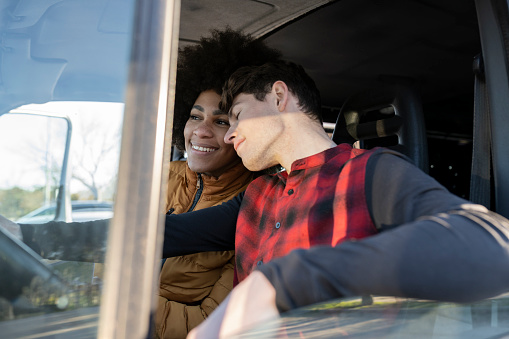 young multicultural couple in love inside the car traveling on the road