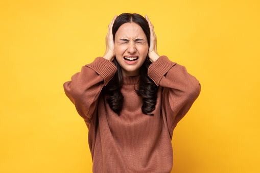 Photo of young women in winter wear standing on yellow background