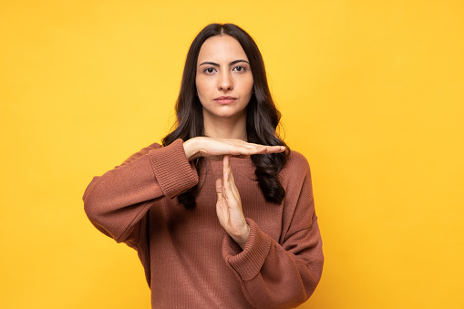 Photo of young women in winter wear standing on yellow background