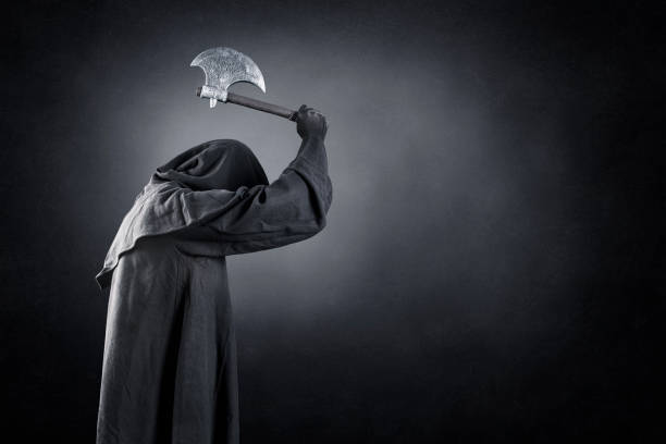 Man in black hooded cloak with axe over dark misty background
