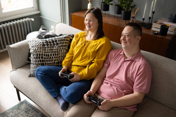 自宅でビデオゲームをしている特別なニーズを持つ幸せなカップル。 - gamer watching tv adult couple ストックフォトと画像