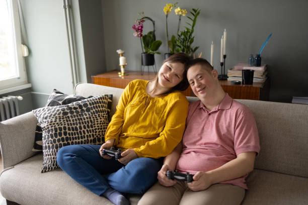 家でビデオゲームをしているダウン症ののんきなカップル。 - gamer watching tv adult couple ストックフォトと画像