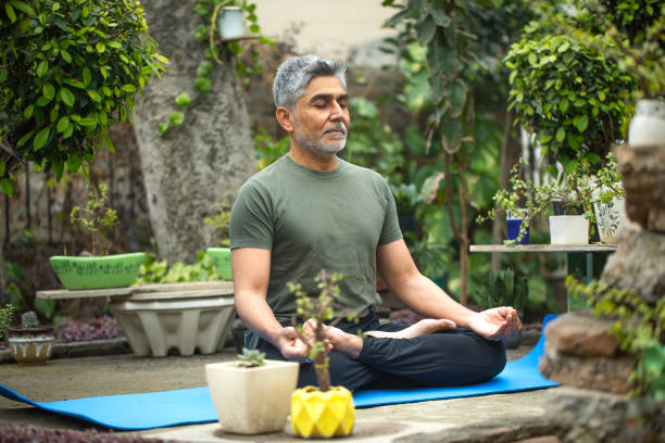 istock Old man meditating on yoga mat in yard 1952221744