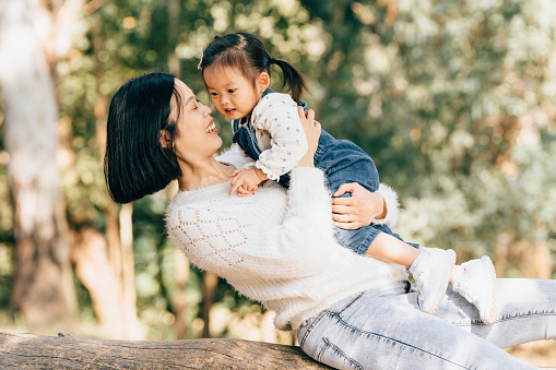 Portraits of an young asian mother and baby daughter spending time happily in a forest on a sunny day.