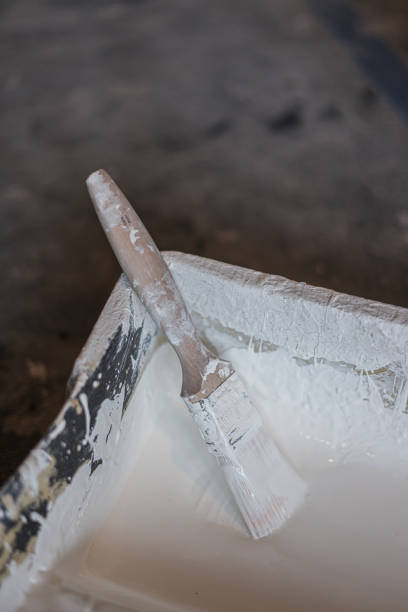 A paintbrush with white bristles and a blue handle on a wooden surface.