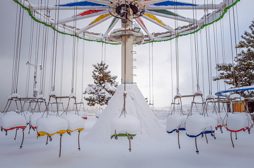 In winter, the children's carousel is covered with snow.